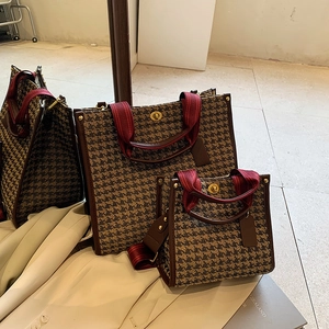 Large geometric tote bag with brown leather trim and red striped handles in mirror view