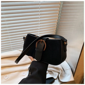 Close-up of black suede and leather patchwork underarm bag with bronze buckle detail