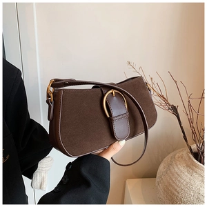 Detail of a vintage dark brown suede and leather shoulder bag with golden buckle hardware