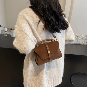 Chic brown leather crossbody square bag with gold buckle shown on beige knit sweater