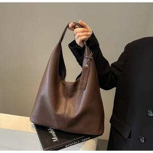 Close-up of coffee brown lychee textured leather tote bag with thick strap and hangtag