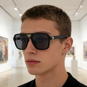 Close-up of a man wearing square black sunglasses with golden metal detailing