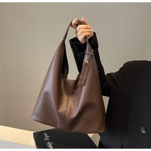Detailed macro view of dark brown lychee pattern leather tote with branded tag