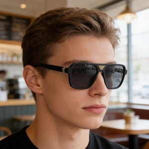 Detail view of square black sunglasses with gold geometric bridge on a male model