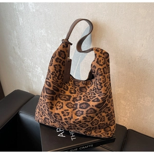Close-up of leopard print tote bag texture and dark brown leather strap on a sofa