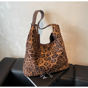 Detail of leopard print tote bag featuring brown lychee grain leather handles and tags