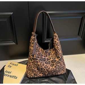 Detail of leopard print tote bag featuring brown leather strap on a stylish dark background