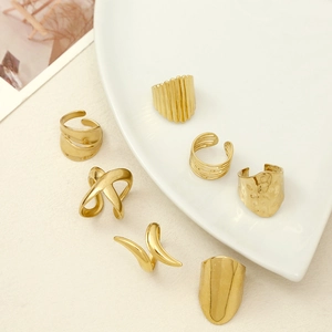 Set of 7 gold-toned chunky rings in minimalist and bohemian styles on a white texture