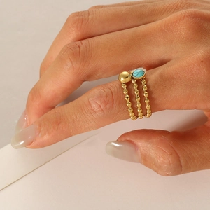 Close-up of bohemian gold beaded rings set with turquoise stone on finger