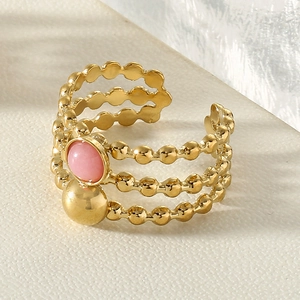 Close-up of triple-layered gold titanium steel ring with pink gemstone and bead detail