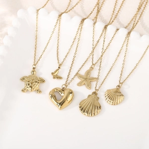 Gold stainless steel ocean necklace set with turtle, starfish, and heart charms in white dish