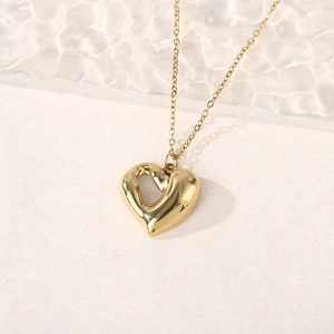 18K gold plated hollow heart pendant necklace with fine chain on minimalist background