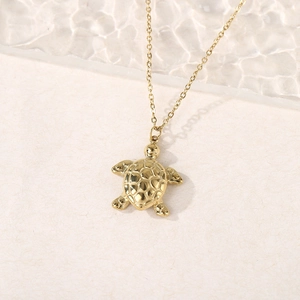 Macro detail of golden sea turtle pendant featuring a polished finish and realistic texture