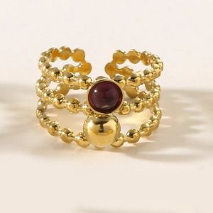 Detailed view of triple-layered beaded gold ring featuring a purple gemstone inlay
