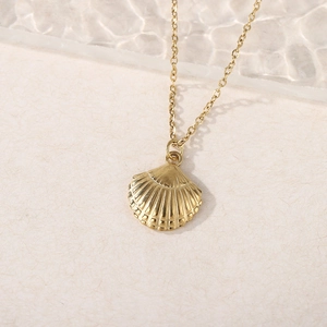 Detailed close-up of golden shell pendant with embossed texture on O-chain necklace