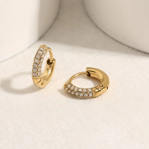 Dettaglio di orecchini huggie in oro 18K con tre file di zirconi bianchi micro-paved