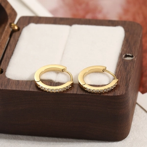 Élégantes boucles d'oreilles créoles dorées avec zircons sur une boîte à bijoux en bois