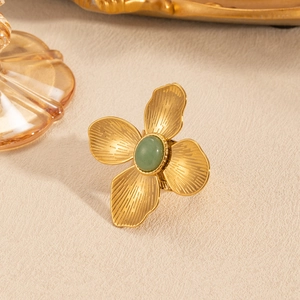Detailed macro view of vintage petal ring with green natural stone on textured background