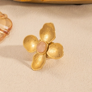 Macro detail of gold flower ring with textured petals and oval natural stone inlay
