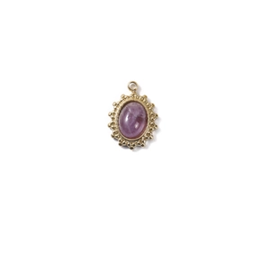 Macro detail of oval purple gemstone pendant with golden sunburst beaded metal frame