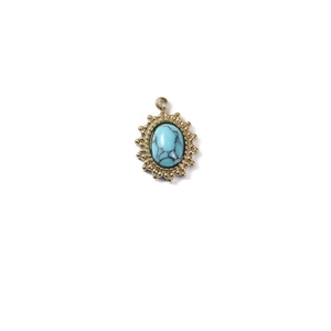 Close-up of vintage sun-shaped gold pendant with oval turquoise stone and wavy edges