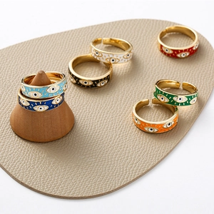 Colorful enamel evil eye open rings in seven colors on a textured beige display