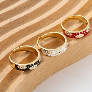 Detailed close-up of three colorful evil eye open rings in gold finish on wood