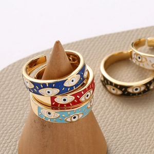 Detail of colorful enamel evil eye open rings on a wooden stand in bohemian style