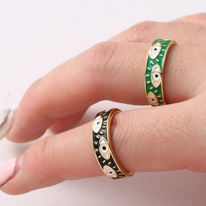 Detail of gold evil eye rings with black and green enamel inlay on female hand
