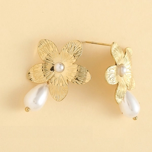Macro detail of gold flower earrings with pearl drop and radial brushed texture petals