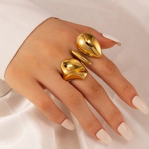 Exaggerated geometric hollow gold ring in 18K titanium steel worn on hand over silk fabric