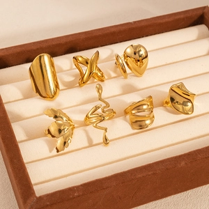 Detailed set of seven golden titanium steel geometric rings on beige velvet display