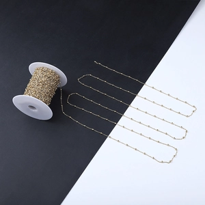 Macro shot of gold-plated stainless steel paperclip chain on a white plastic reel