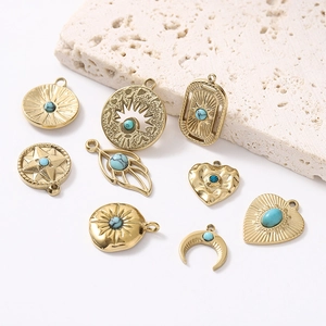 Vintage gold moon and heart pendants with turquoise stones on a beige stone background