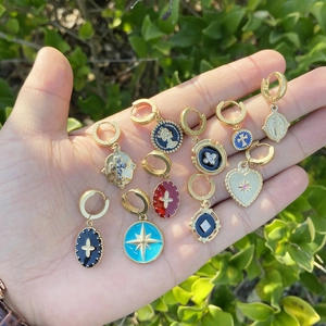 Detail of 11-piece gold huggie earrings set with colorful enamel star and coin pendants