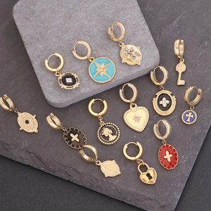 Close-up of gold-plated star and heart charms with enamel and zircon on dark stone background