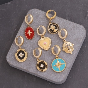 Detailed macro view of seven gold-plated hoop earrings with cross and star charms