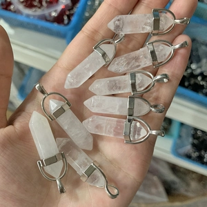 Hand holding white crystal hexagonal column pendants with silver metal caps for jewelry