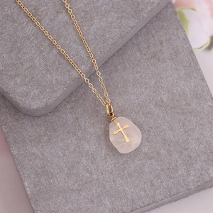 Gold necklace featuring a natural pink stone pendant with a delicate cross inlay