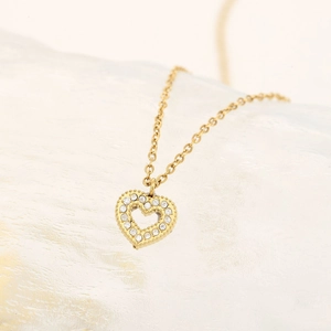 Collier pendentif coeur doré orné de zircons brillants sur fond blanc élégant et épuré