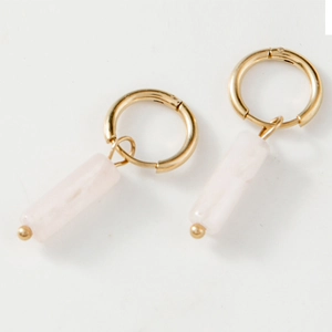 Détail de créoles dorées avec pendentifs cylindriques en pierre rose naturelle et perles