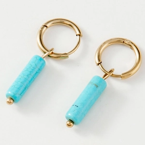 Gros plan de boucles d'oreilles créoles dorées avec pendentifs turquoise et texture marbrée