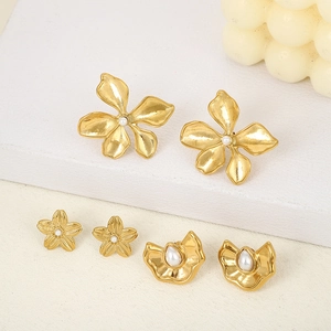 Trois paires de boucles d'oreilles fleur en or avec perles sur un support minimaliste