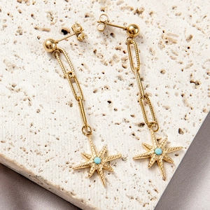 Bohemian gold paperclip chain earrings with star pendants on a stone display