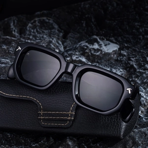 Lunettes de soleil carrées noires avec charnières en T et étui en cuir sur pierre