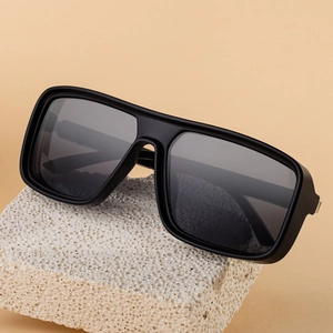 Square frame polarized sunglasses in black with grey lenses on a minimalist stone
