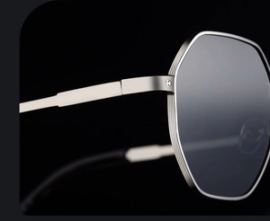 Macro detail of silver metal hinge with H logo engraving on square frame sunglasses