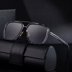 Square pilot sunglasses with dark lenses and sleek metal frame on a textured black case