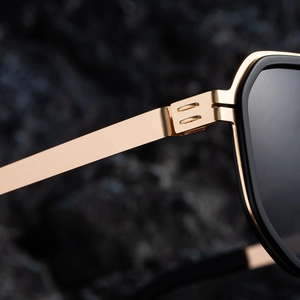 Close-up of golden metal hinges and black matte frame on square polarized sunglasses