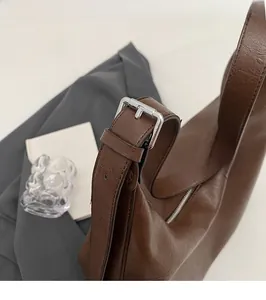 Detail of glossy vintage brown leather texture and silver metallic buckle on shoulder bag